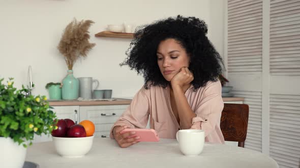 African American Woman Looks at Content on Smartphone Rejoices Celebrating Victory Received Good alt