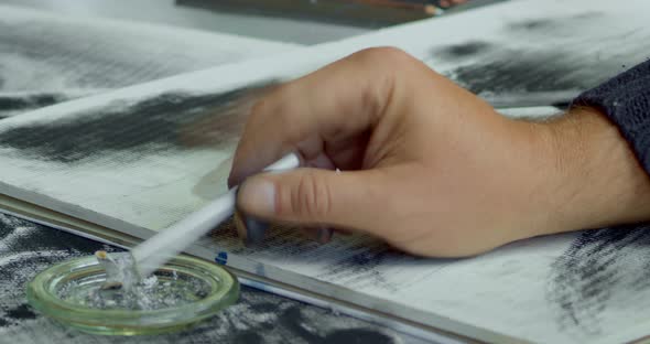 A hand with a cigarette in a decomposed charcoal drawing. Tapping off the ashes of a cigarette and c alt