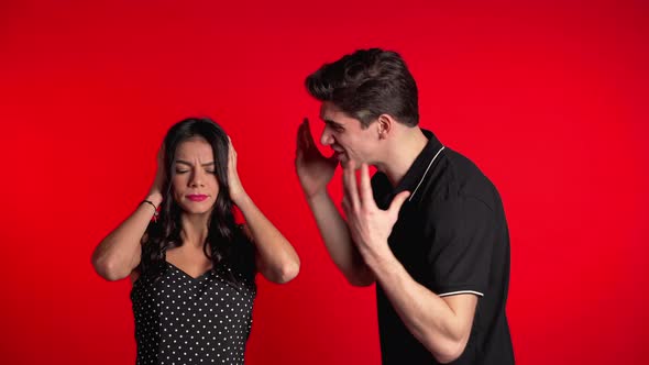 Young Man Emotionally Screaming at His Wife or Girlfriend on Red Background alt