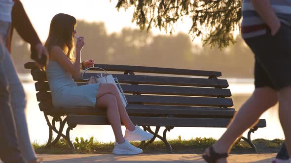 Lonely Woman Sitting Alone on Lake Shore Bench on Warm Summer Evening alt