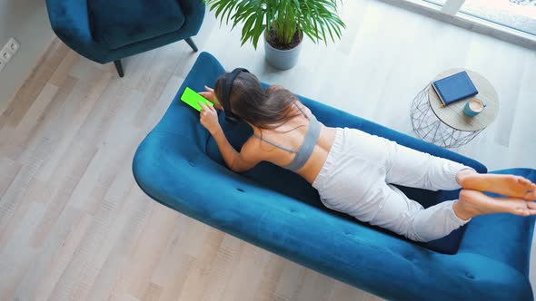 Woman in Wireless Headphones Listening to Music and Using Mobile Apps or Communicates on Social alt