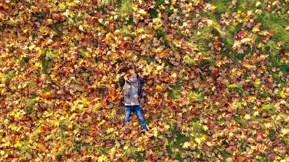 Cute girl lies on the bright autumn foliage in the park and dreams alt