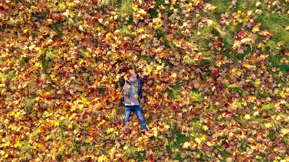Cute girl lies on the bright autumn foliage in the park and dreams