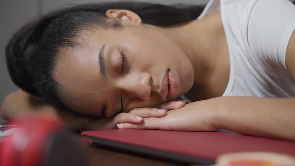 Closeup Face of Fatigued African American Young Woman Sleeping on Table in Home Office alt