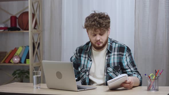Young Man in Checkered Shirt Typing on Laptop Keyboard alt