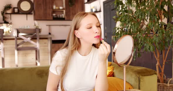 Young woman applying lipstick paints lips prepare getting ready in front of mirror alt