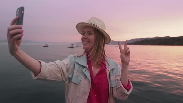 Happy Smiling Woman Using Funny Face Mask on Smartphone Outdoors Sunset at Lake alt