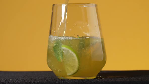 Close-up of a refreshing soda tonic. Pour sparkling water into a glass with lime and ice.