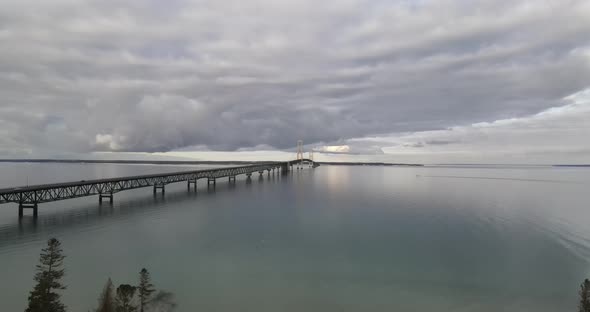 Mackinac Bridge drone videoing down to Old Mackinac Point Lighthouse in winter. alt