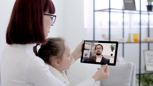 Mother and Her Daughter Sitting and Relaxing on Sofa at Home and Talking on Video Call with Smiling alt