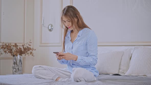 Young Female Texting Use Mobile in Bedroom