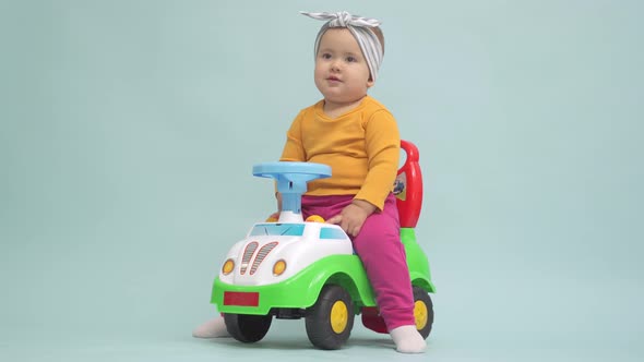 Toddler 12-17 months old sits on a toy car and tries to ride it pushing off with his feet alt