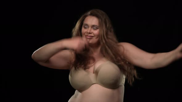 Joyful Dance of Cheerful Plus Size Woman at Black Background alt