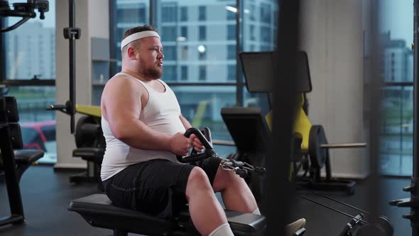 Overweight Funny Man Lifting Blocks Doing Chest Exercises Training on Block Device and Gym Equipment alt