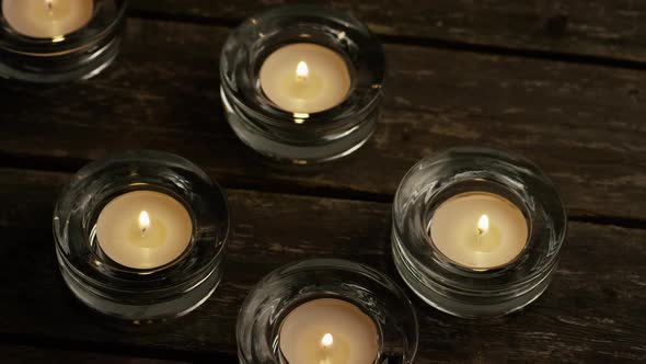 Tea candles with flaming wicks on a wooden background - CANDLES 001 alt