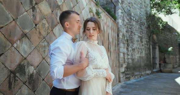 Romantic wedding couple standing and walking in old town in Montenegro. alt