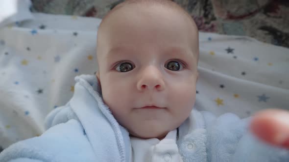 Funny Child Lies in Bed Looks at the Camera and Shows Different Emotions