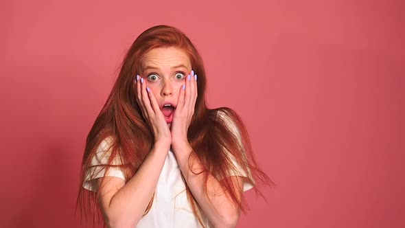Scared Shocked Redhaired Ginger Woman in Pink Studio Background alt