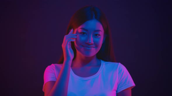 Young Positive Asian Woman Tapping on Temple Showing at Her Brain and Smiling to Camera in Bright alt