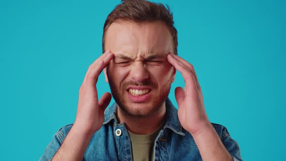 Young Handsome Man Standing Over Isolated Blue Background Suffering From Headache