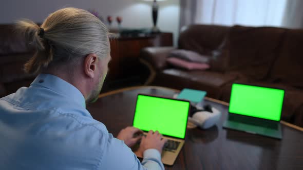 Shooting Over Shoulder of Concentrated Freelancer Messaging Online on Green Screen Laptop in Home alt