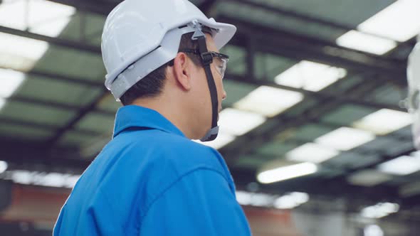 Asian automotive mechanic repairman look under car condition in garage. alt