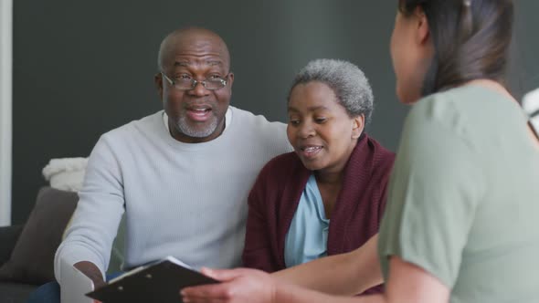 Smiling asian female counselor advising to african american senior couple alt
