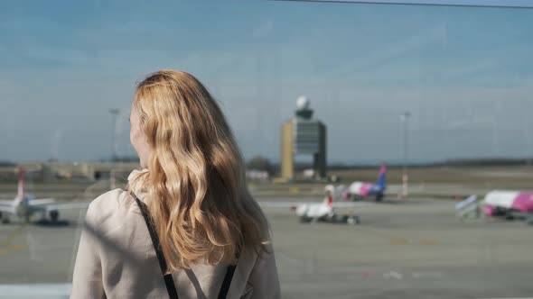 woman looks at planes standing on the airport runway