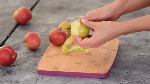 Hands Peeling Apple on Wooden Board