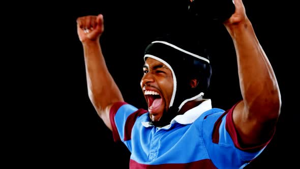 Excited professional rugby sportsman holding a trophy alt