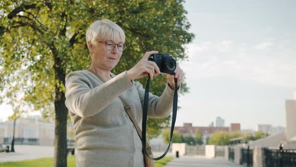 Mature Woman Taking Pictures of Beautiful City Using Professional Camera on Summer Day alt