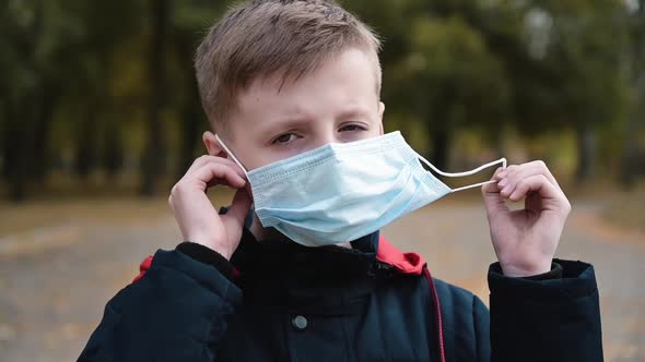 Child Boy Takes Off His Medical Mask Outdoors