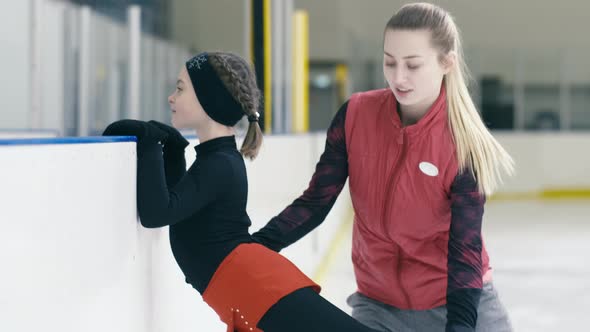 Figure skater listening to her trainer's comment about leg position