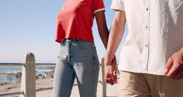 Couple holding hands and walking on beach promenade 4k