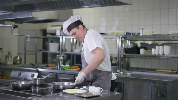 Portrait of Male Cook in Uniform Cleaning Kitchenware in Restaurant Kitchen Indoors alt