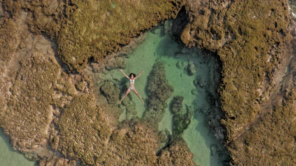 Aerial Footage of Female Person in White Bikini Laying on Natural Reef in the Ocean