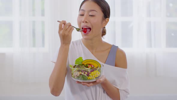Healthy Young Asian woman eat mixture of vegetables Fresh Salad at home alt