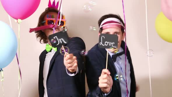 Funny male friends dancing with a sign in love in photo booth alt
