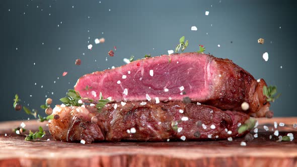 Super Slow Motion Shot of Seasoning Falling on Grilled Beef Meat Slice on Wooden Board at 1000Fps alt