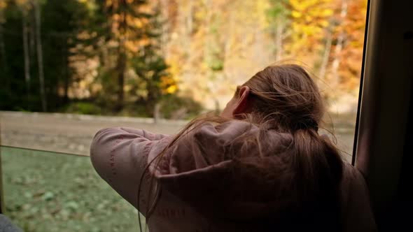 Woman leaned out of the window of the steam train Mocanita moving through a forest, Romania. Slow mo alt