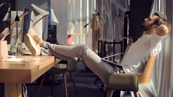 Successful Serious Lazy Man Sitting On Workplace And Relaxing. Overworked Employee Taking Break. alt