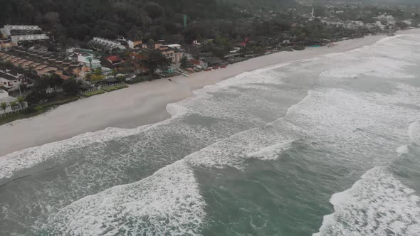 Drone footage of the beach above the sea, mountain in front of the sea, cloudy day, waves, landscape alt