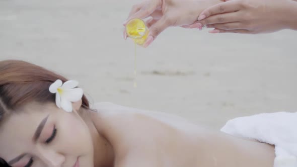 Beautiful happy young asian woman sexy thai massage on back with masseuse on the beach. alt