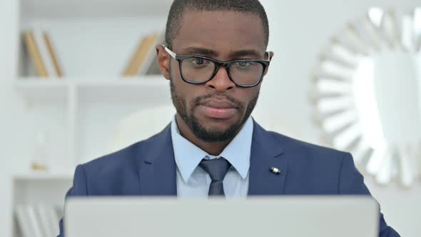 Portrait of African Businessman Thinking and Working on Laptop alt