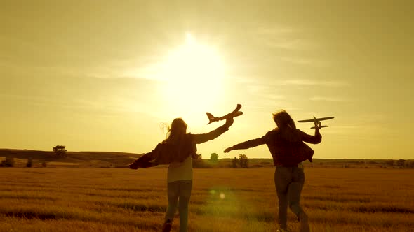 Dreams of Flying. Happy Childhood Concept. Two Girls Play with a Toy Plane at Sunset alt