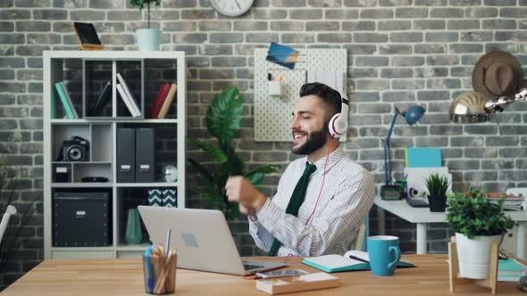 Cheerful Guy Listening To Music Singing Dancing at Work Using Headphones alt