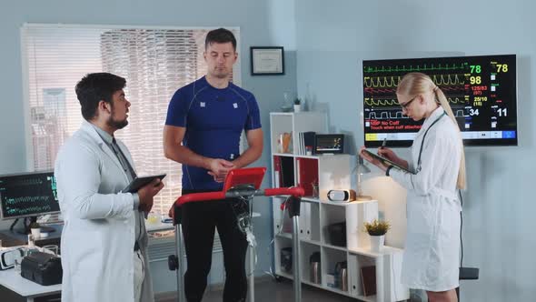 Mixed Race Sports Scientist Explaining Athlete EKG Data During Treadmill Testing alt