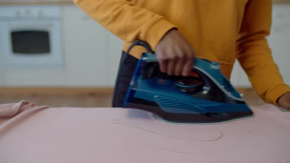 Closeup of Female Hand Ironing Clothes with Electric Iron alt