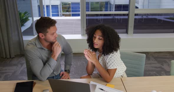 Young office executives discussing over laptop in a modern office alt