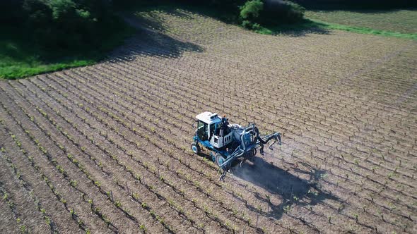 Aerial view of tractor spraying pesticides or water on field with sprayer at spring